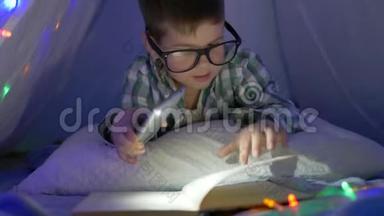 在家上学，戴眼镜的男孩拿着一部智能<strong>手</strong>机，<strong>手</strong>里拿着<strong>手</strong>电筒，在<strong>帐</strong>篷里看书